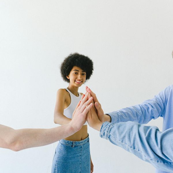 Diverse group of people smiling in a bright, modern yoga studio.